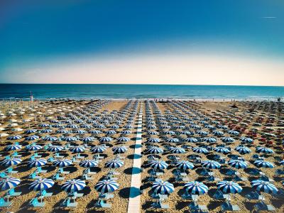 Spiaggia con ombrelloni blu e bianchi allineati, vista mare.