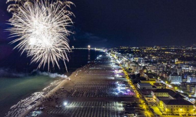 Feuerwerk erleuchtet den Strand bei Nacht, Panoramaansicht der Küstenstadt.
