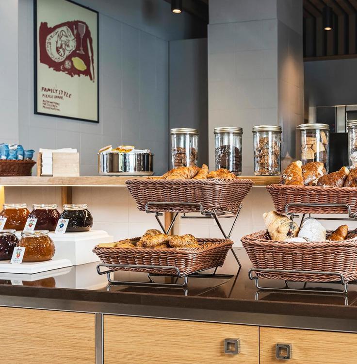 Frühstücksbuffet mit Croissants, Marmeladen und Keksen in Glasgefäßen.