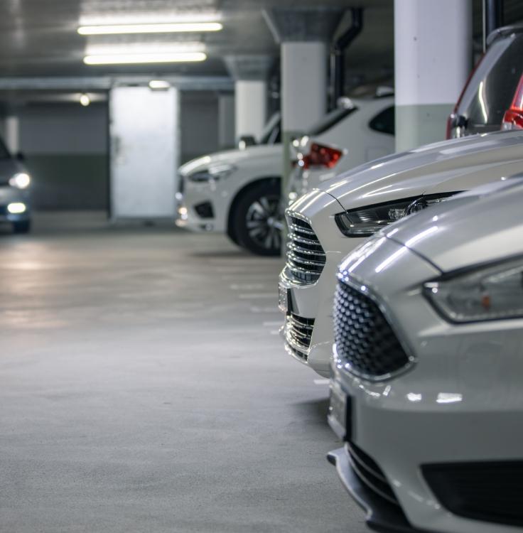 Parcheggio sotterraneo con auto bianche allineate.