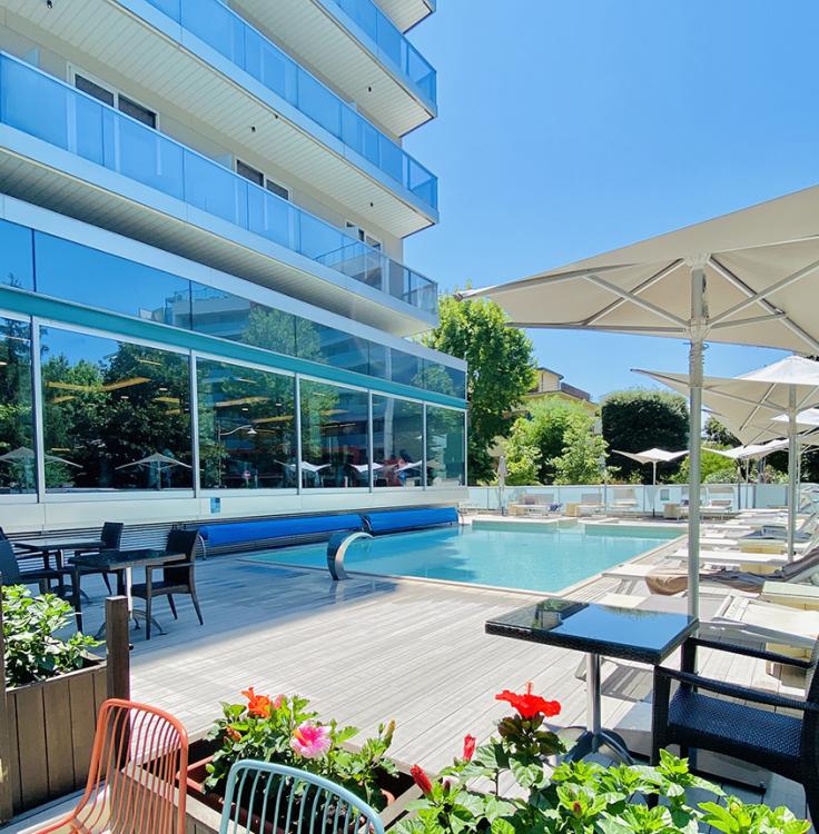 Modernes Hotel mit Außenpool, Liegestühlen und Sonnenschirmen.